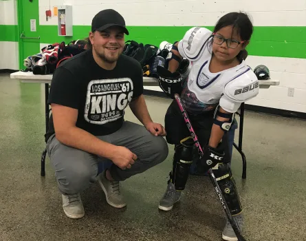 A young hockey participant with a volunteer, photographed for the Thunder Bay PRO Kids program.